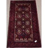 Persian Baluchi red ground rug, repeating gul design, with purple elements,