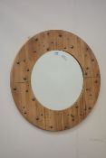 Circular riveted pine wall mirror fitted with bevelled glass,