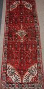 Hamadan runner with central cruciform medallion, over red ground with allover floral design,