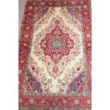 Persian Tabriz carpet, central floral medallion over cream ground spandrels red floral borders,