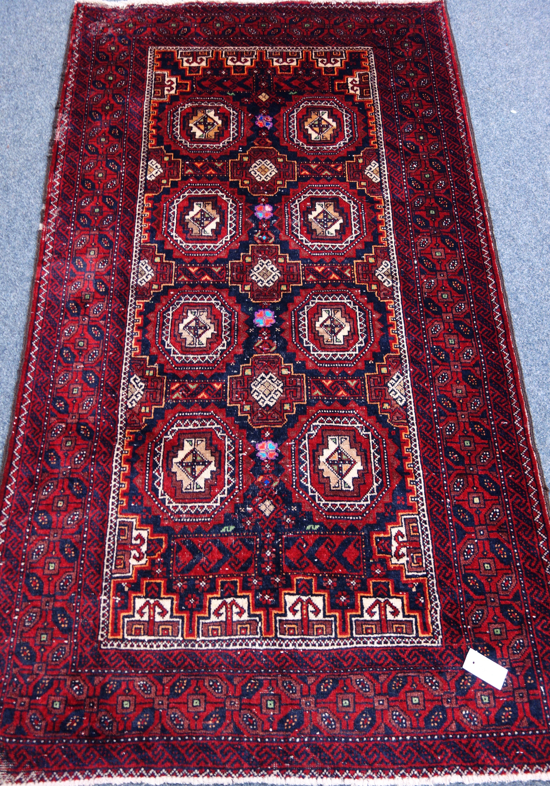 Persian Baluchi red ground rug, repeating gull design, with purple elements,