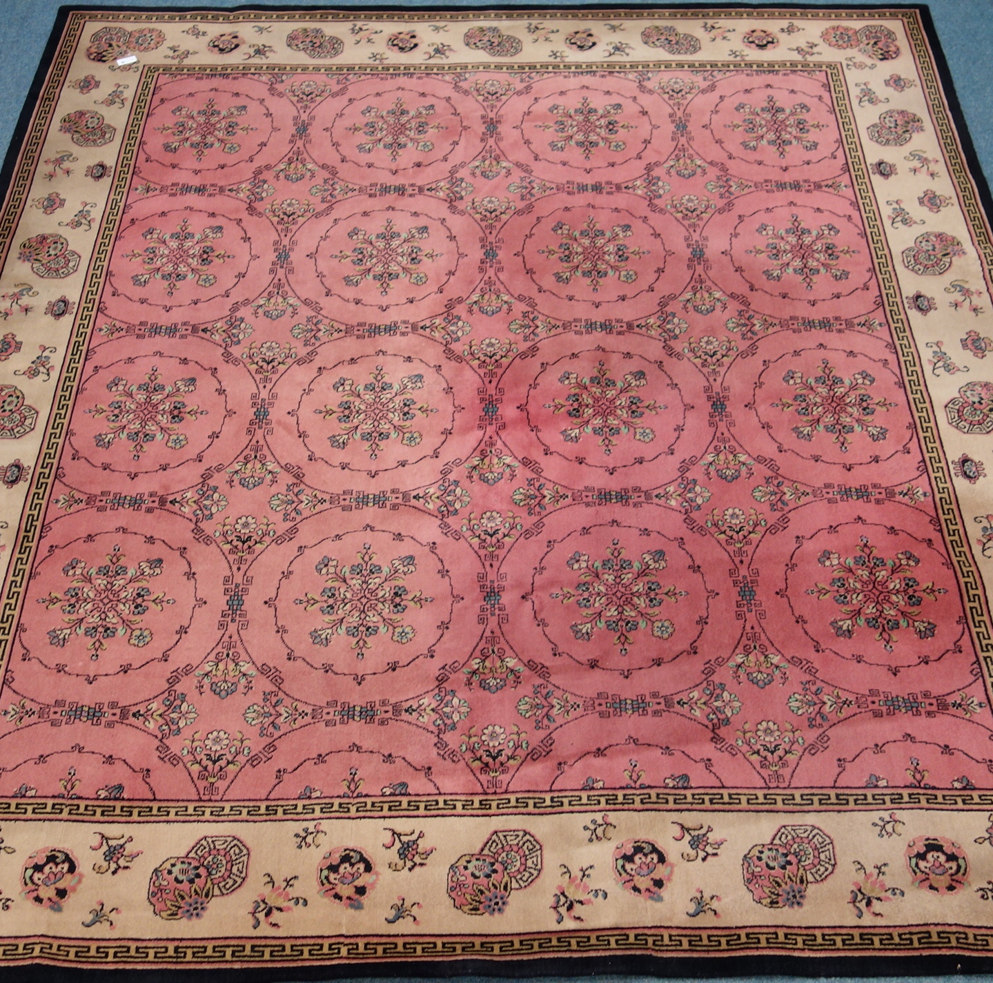 Edwardian rug carpet, coral ground with repeating stylised flower design,