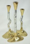 Three graduated brass and steel contemporary candle sticks,