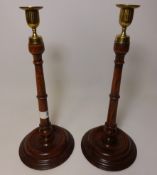 Pair of turned oak candle sticks with brass tops,