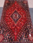 Persian Shiraz hand knotted red ground rug, stylised motifs,