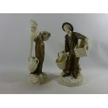 Amphora type porcelain figures of a male holding wicker baskets and a lady holding water jugs (2)