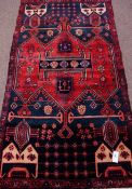 Persian Baluchi red and blue ground rug, stylized decoration,