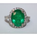 Oval Brazilian emerald and diamond cluster white gold ring with diamond shoulders hallmarked 18ct,