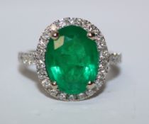Oval Brazilian emerald and diamond cluster white gold ring with diamond shoulders hallmarked 18ct,