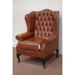 Wingback armchair upholstered in buttoned tan leather,
