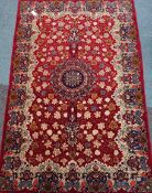Persian Keshan rug, stylized central rosette medallion over red ground,