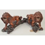 A pair of Chinese carved hardwood lions with glass eyes and bone teeth, length 27cm, height 16.