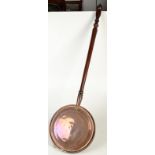 A copper warming pan with turned, fruitwood handle.