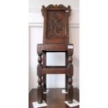 A carved oak child's correction chair, height 94cm, width 29cm.