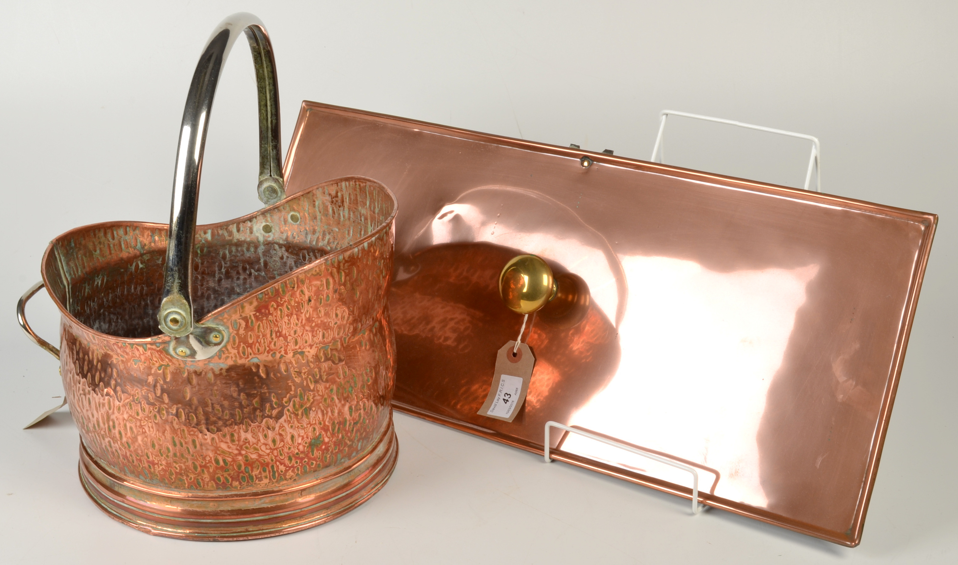 A copper fire draw plate with a brass handle, width 61cm and a copper and brass coal helmet.