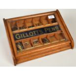 An early 20th century Gillott's Pens oak display case with a hinged lid opening onto twelve