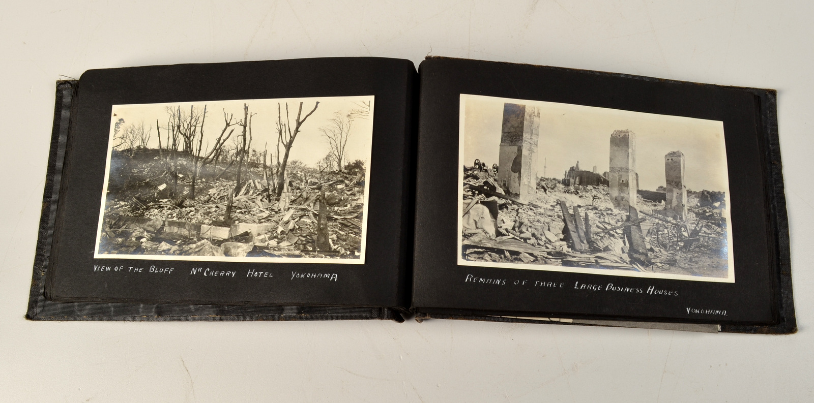 A small photograph album, gold embossed with "THE GREAT EARTHQUAKE YOKOHAMA. 1-9-23. JAPAN. H.M.S.