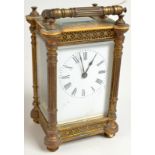 A brass carriage clock, the corners cast with classical columns between floral friezes,