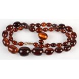 A simulated amber necklace, 79g. including two loose matching beads and a 9ct. gold clasp.