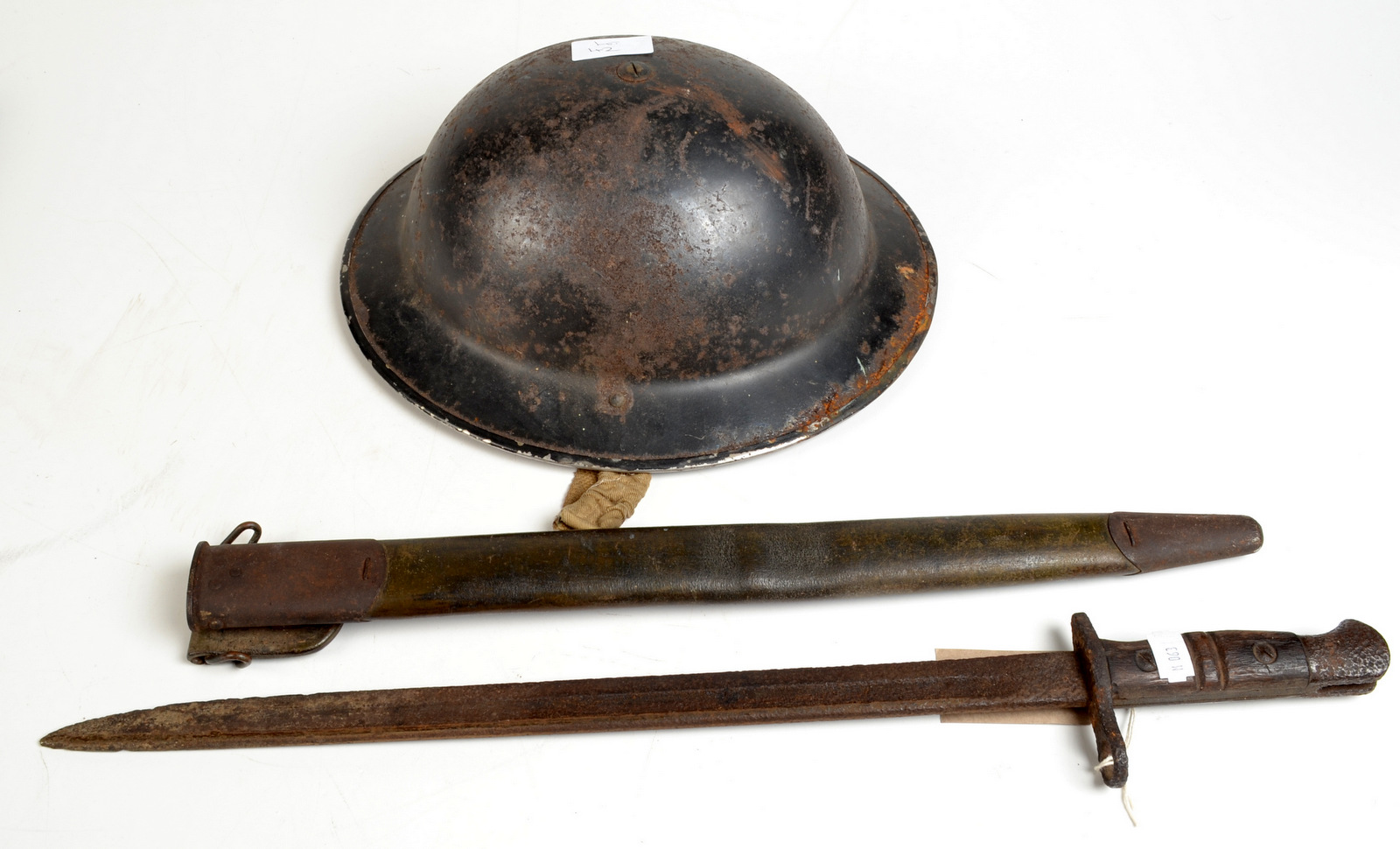 A Brodie helmet and a Remington bayonet in its original leather sheath.