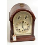 A bracket clock with Westminster chime in an arched mahogany case,