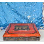 A Chinese red lacquered box with a black gilt decorated cartouche to the cover, enclosing figures,