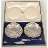 A pair of shell shaped butter dishes retailed by Harrods, with butter knives and original box.