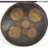 An Indo Persian convex hide shield with four iron bosses and five brass panels embossed with