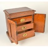 A miniature oak chest fitted three drawers behind doors.