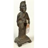 A Chinese bronze figure of a house god or court figure standing upon a shaped base and wearing