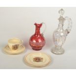 A Clarice Cliff 1953 trio, a cranberry enamelled claret jug and one other glass claret jug.