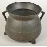 A 17th century bronze twin handled cauldron standing on three cast feet, diameter 23.