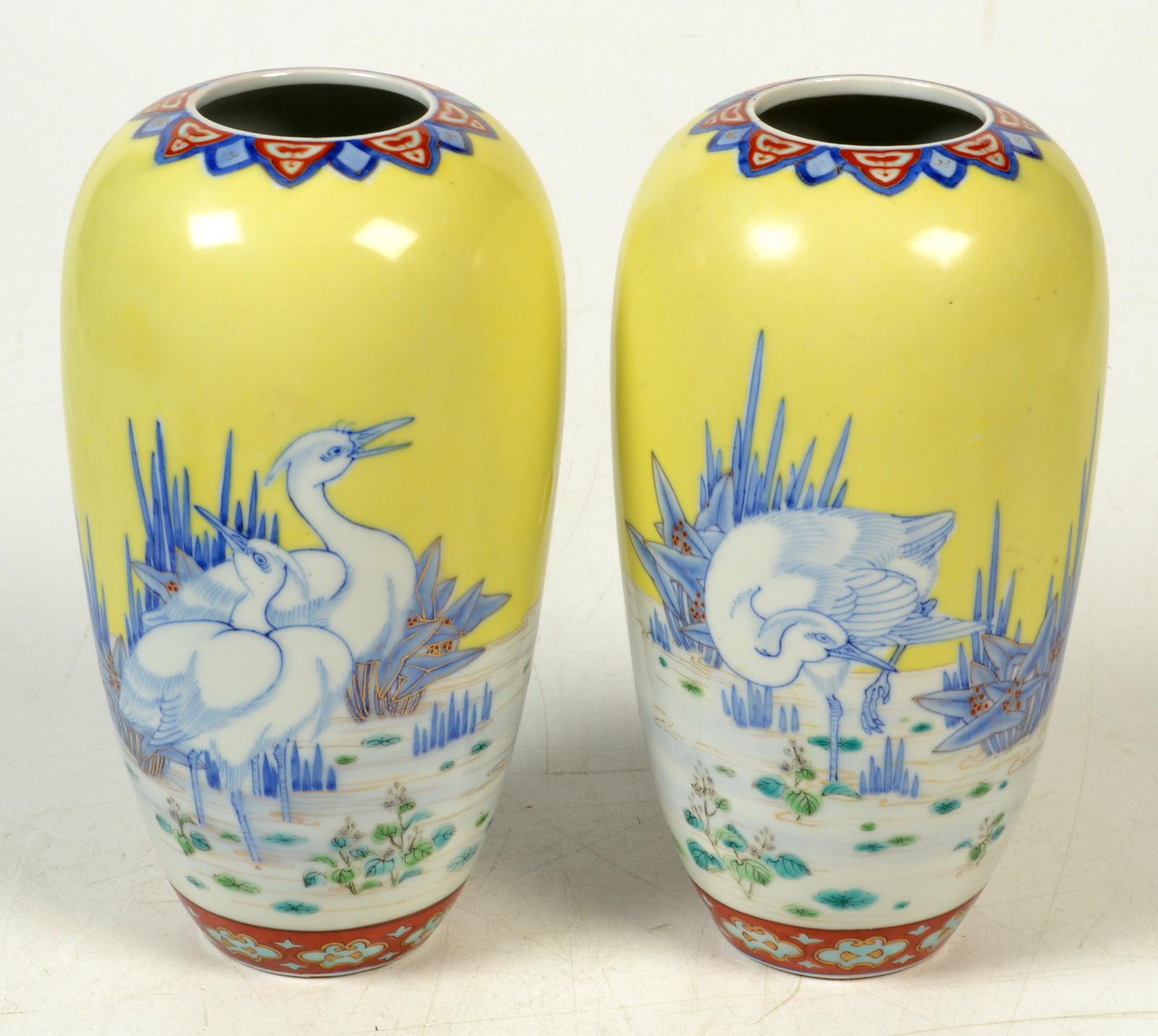 A pair of Japanese vases, the yellow ground decorated with wading herons among reeds,