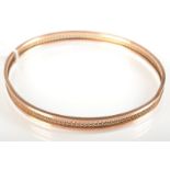 A 9ct. gold bangle with a pierced central band, 9.3g.