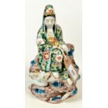 A Japanese porcelain figure of a seated Guanyin, around the rock on which she sits,