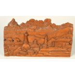 A carved wood panel showing a Tibetan scene with central stupa.