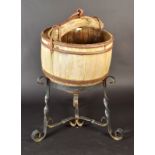 A wooden well bucket on wrought iron stand.