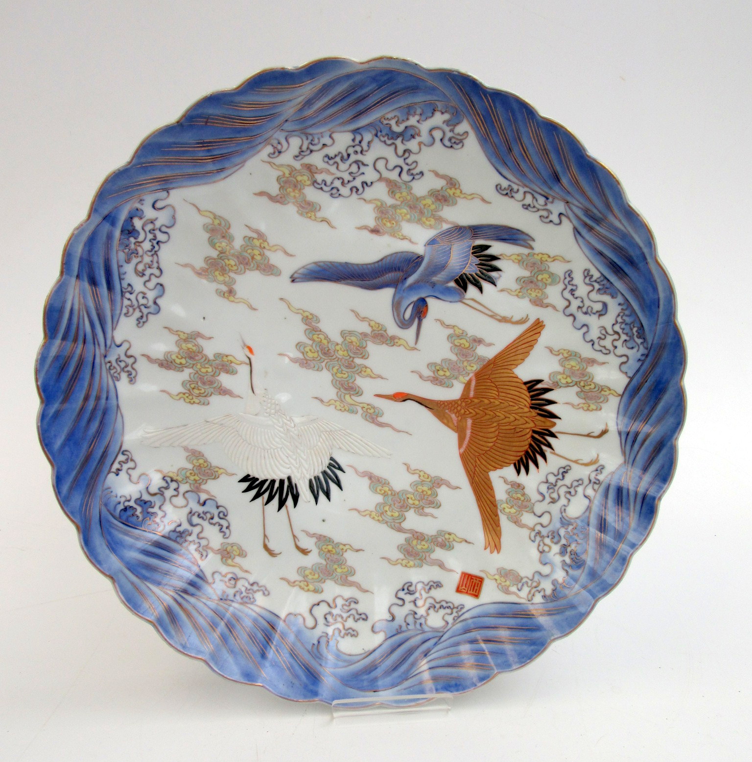 A Japanese Fukagawa dish, decorated with cranes in flight and bands of cloud,