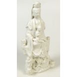 A late 18th century Fukien Dehua figure of a seated Quanyin supporting a child acolyte on her lap,