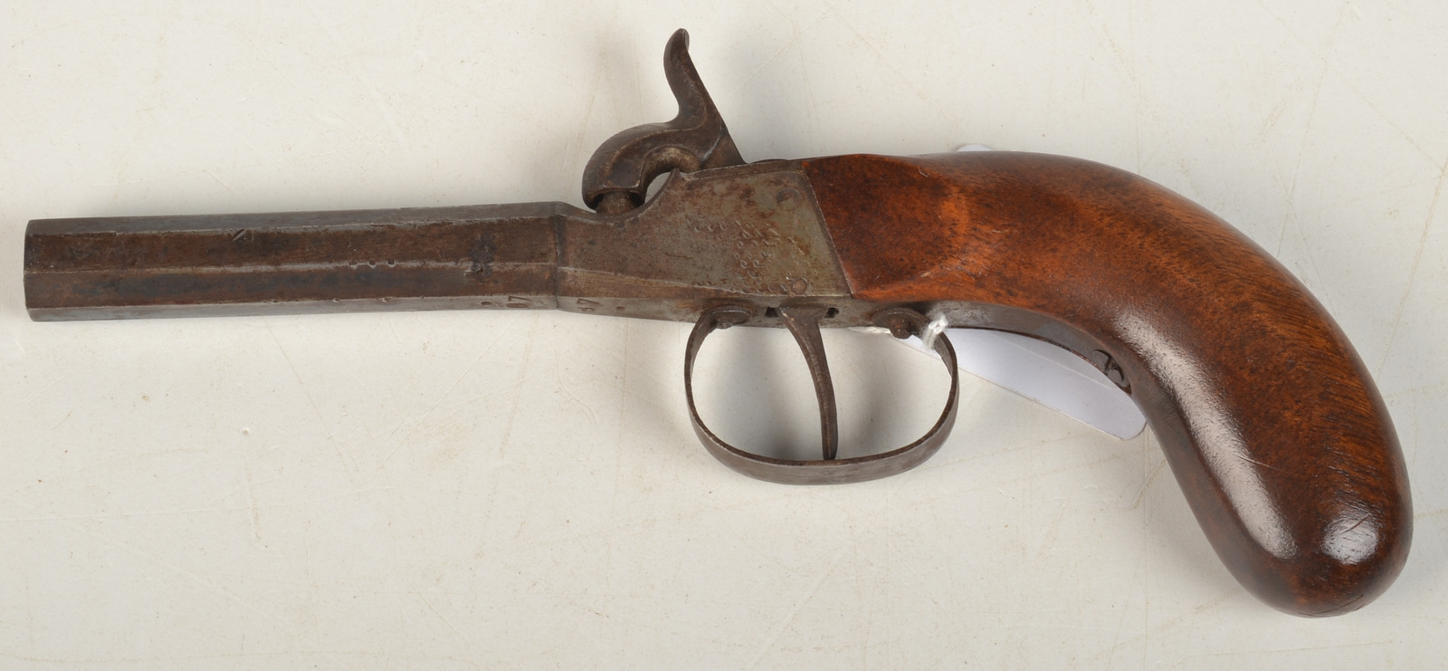 A 19th century box lock pocket pistol with octagonal turn-off barrel and walnut stock.