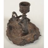 A 19th century iron chamberstick cast with a merman and two stylised fish, height 12cm.