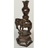 A Chinese bronze figure, Ming Dynasty, cast as an elephant carrying a vase on a pierced plinth base,