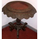 An Indian circular, carved, pedestal occasional table standing on three lion carved feet,