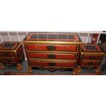 A lavish ebonised and carved gilt commode of three long drawers with gold painted red ground panels