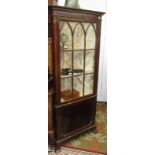 A Regency style mahogany standing corner cupboard with lancet glazed upper door over a panelled