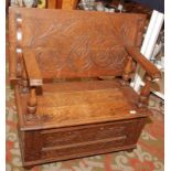 An oak pre war monks bench, the carved back above a hinged seat above a floral and leaf carved base,