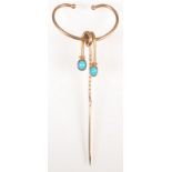 A patent gold pin with horned finial and turquoise set drops.