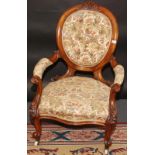 A Victorian walnut buttoned balloon back open armchair with carved cabriole legs.