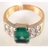 A gold ring set an emerald flanked by two groups of four diamonds.