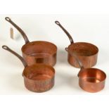 A set of four copper cylindrical graduated pans with iron handles.